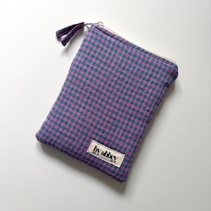 Könnte beinhalten: Ein rechteckiges Stoffetui mit einem violetten und blaugrünen Vichy-Karomuster. Das Etui verfügt über einen Reißverschluss an der Oberseite mit einem passenden Stoffanhänger und ein kleines weißes Etikett mit der Aufschrift by abbey.