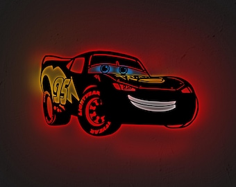 May include: A black Lightning McQueen car-shaped neon sign with red and yellow accents. The number "95" is visible on the side, and the tires have the word "LIGHTYEAR" on them. The car has blue eyes and a smiling mouth.