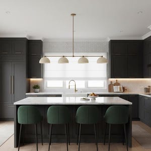 May include: A kitchen featuring dark charcoal cabinetry, a white marble-topped island, and four dark green upholstered stools. A linear brass pendant light with four dome-shaped shades hangs above the island, centered in front of a window.