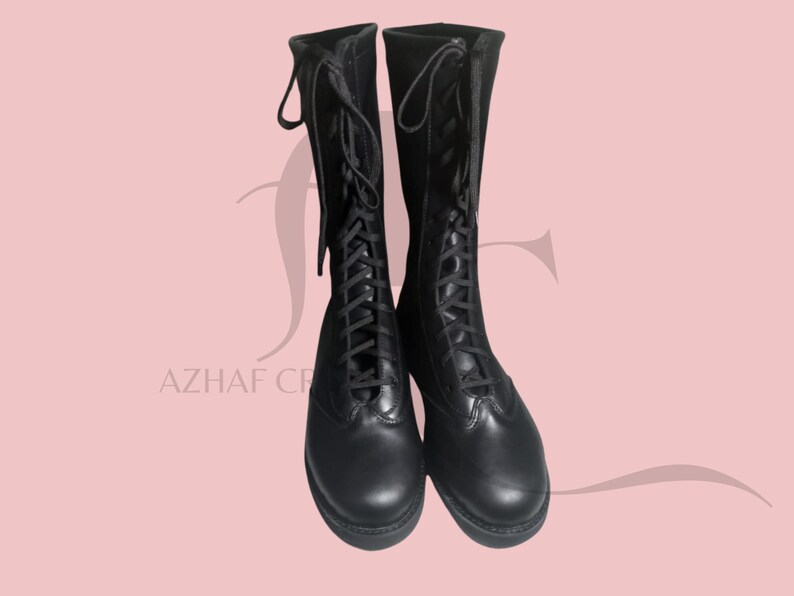 K&ouml;nnte beinhalten: Ein Paar schwarze, kniehohe Stiefel mit Schn&uuml;rdesign. Die Stiefel haben eine runde Spitze und eine robuste Sohle. Die Schn&uuml;rsenkel verlaufen &uuml;ber die Vorderseite der Stiefel, und die Oberseite der Stiefel hat eine Schlaufe zum einfachen Ziehen.