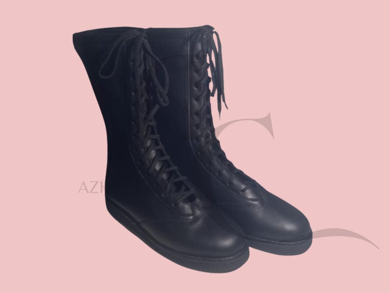 K&ouml;nnte beinhalten: Ein Paar schwarze, kniehohe Stiefel mit Schn&uuml;rdesign. Die Stiefel haben eine glatte, matte Oberfl&auml;che und eine runde Spitze. Die Schn&uuml;rsenkel verlaufen &uuml;ber die Vorderseite der Stiefel, und die Sohlen sind flach.