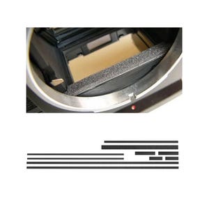 May include: Close-up of a camera lens mount with a black foam insert. The lens mount is silver and has a circular shape. The interior of the camera body is visible, with a tan-colored surface.