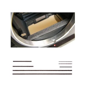 Könnte beinhalten: Nahaufnahme des Inneren einer Kamera, die eine schwarze Schaumstoff-Lichtdichtung und einen silbernen Metallrahmen zeigt. Die inneren Komponenten der Kamera sind sichtbar, mit Fokus auf den Lichtdichtungsmechanismus. Mehrere schwarze Klebestreifen sind ebenfalls vorhanden.