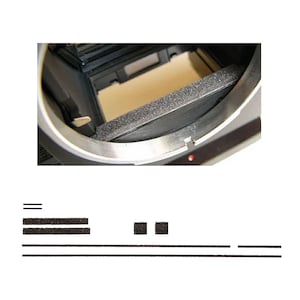 May include: Close-up of a camera interior with a black foam light seal and a silver metal frame. The image also shows several black foam strips and squares, likely replacement parts for the camera.