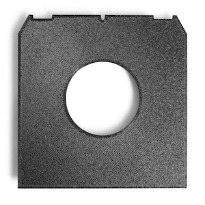 May include: A square, black, textured object with a circular hole in the centre. The object has a diagonal pattern across its surface and a notched top edge. It is likely a component or part of a larger product.