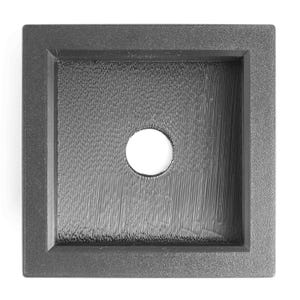 May include: A square, dark gray sink with a textured interior and a central, circular drain hole. The sink has a raised, rectangular border. The interior texture consists of vertical lines.