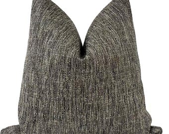May include: A decorative throw pillow with a textured, woven fabric in shades of gray, brown, and beige. The pillow has a classic shape and is designed for home decor.