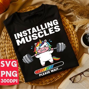May include: Black t-shirt featuring the text "INSTALLING MUSCLES" and a cartoon unicorn lifting weights. The unicorn has a rainbow mane and tail. A loading bar with "PLEASE WAIT..." is below the unicorn. File type information is also visible.