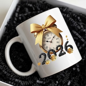 May include: White ceramic mug featuring a gold clock design with the year 2026, a gold bow, and black and gold floral accents. The mug is presented in a white gift box with black shredded paper.