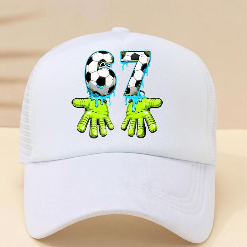 May include: White baseball cap with a mesh back and a curved brim. The cap features a graphic of the numbers "67" in a soccer ball design, with green hands and blue dripping accents. The cap is a sporty accessory.