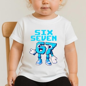 May include: White t-shirt with the words "SIX SEVEN" in blue pixelated font. Below the text are the numbers 6 and 7, designed as cartoon characters with blue bodies, white gloves, and blue shoes. The shirt is for children.
