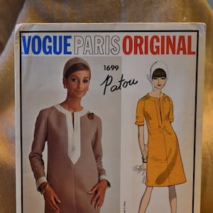 May include: Vogue Paris Original sewing pattern number 1699 by Patou. The pattern features two dress designs, one in a beige color with a white trim and the other in a yellow color.