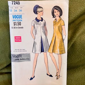 May include: Vintage Vogue sewing pattern number 7245 for a dress. The pattern is for sizes 12, 34, and 36. The pattern is $1.50 and $1.65 in Canada. The pattern features two illustrations of women wearing the dress.