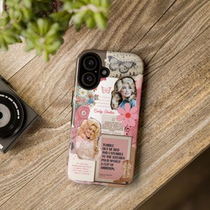 May include: A phone case featuring a collage design with images of Dolly Parton, butterflies, flowers, and text. The case has a brown border and a pink and white background with a quote: "Tumble out of bed and I stumble to the kitchen pour myself a cup of ambition."