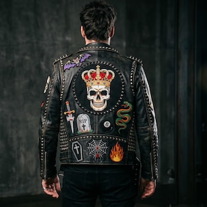 以下が含まれることがあります： シルバーのスタッズとパッチが付いた黒い革のジャケット。パッチには、王冠をかぶったスカル、コウモリ、ヘビ、短剣、墓石、棺、クモの巣、エイトボール、炎が含まれます。 ジャケットはジッパー開閉です。