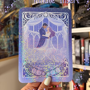 May include: A rectangular Kindle insert featuring a holographic finish and a purple-toned illustration of two figures embracing in front of a large arched window, with a city skyline and floral accents at the bottom and the text Kindle Insert.