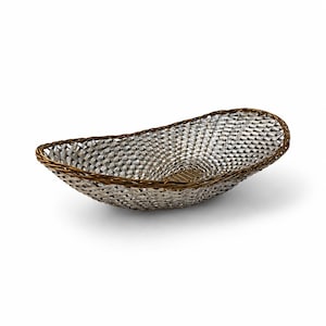 Puede incluir: Una cesta de forma ovalada con un cuerpo de metal plateado tejido con un patr&oacute;n de trama cruzada. El borde est&aacute; construido con un material trenzado de color marr&oacute;n oscuro que proporciona un contraste con el interior plateado reflectante.