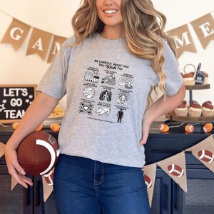 Könnte beinhalten: Ein graumeliertes Kurzarm-T-Shirt mit einem schwarzen Grafikdruck mit dem Titel BE CAREFUL WHAT YOU WISH FOR. Das Design enthält neun kleine Illustrationen mit jeweils einem Textuntertitel, wie zum Beispiel I WISH TO BE FAMOUS und I WISH TO BE RICH.