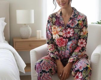 May include: Floral print pajama set in shades of pink, red, yellow, and purple on a black background. The set includes a button-down shirt and matching pants. The pajamas are made of a soft, comfortable material.