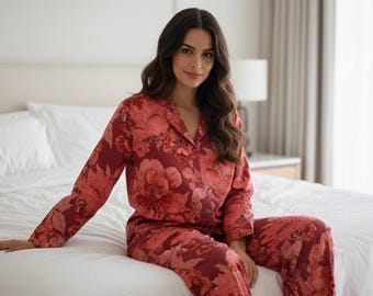 Puede incluir: Conjunto de pijama floral burdeos. La ropa de dormir de dos piezas presenta una parte superior con botones y pantalones a juego. El estampado floral es en tonos rojos y rosas. El pijama está hecho de una tela suave y ligera.