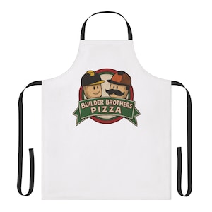 Puede incluir: Delantal blanco con correas negras. Presenta un logotipo de dibujos animados con dos personajes que llevan sombreros y bigotes, con el texto "Builder Brothers Pizza" en una pancarta verde. Para uso en la cocina.