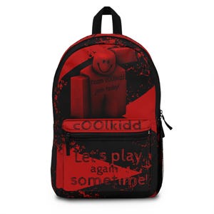 Puede incluir: Una mochila roja y negra con un gráfico de personaje en bloques y el texto team cOOLkidd join today! El bolsillo frontal muestra el texto cOOLkidd y Let's play again sometime! en una fuente desgastada con cierres de cremallera negros.