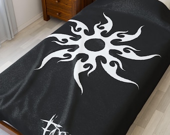 May include: Black and white duvet cover featuring a stylized sunburst design. The sunburst is white and has a tribal-inspired flame pattern. The word "FORSA" is printed in white at the bottom of the cover. The bedding is on a twin-sized bed.
