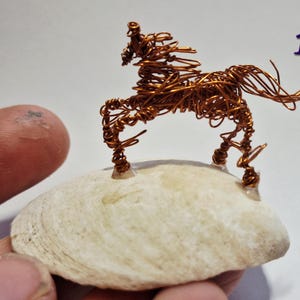 Tiny horse on a shell sketched in 3D in recycled copper wire