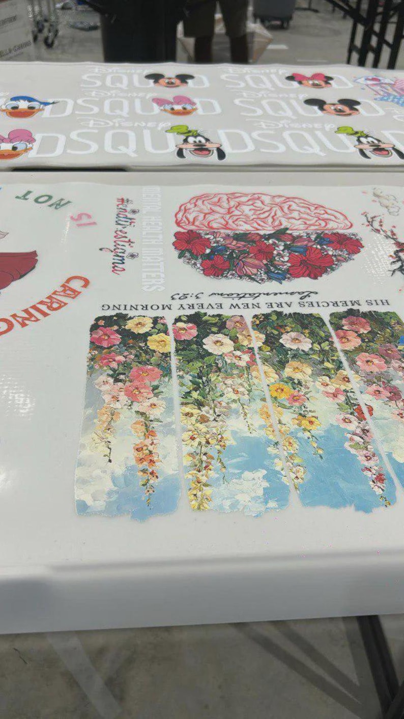 May include: A white surface with Disney character graphics and text. The design includes Mickey Mouse, Donald Duck, and Goofy. Other sections feature floral and brain illustrations with text that reads "HIS MERCIES ARE NEW EVERY MORNING" and "MENTAL HEALTH MATTERS".