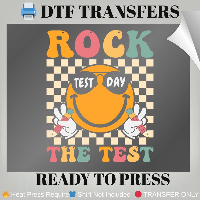 May include: A DTF transfer design with the text "ROCK THE TEST" and a smiling face wearing sunglasses that say "TEST DAY". The design includes pencils and a checkered background. The words "READY TO PRESS" are also included.