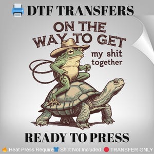 May include: DTF Transfers design featuring a frog wearing a cowboy hat riding a turtle, with the text "ON THE WAY TO GET my shit together". The design is ready to press.