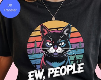May include: Black t-shirt featuring a graphic of a black cat with a colorful sunset background and the text "EW, PEOPLE." The cat has a grumpy expression. The design includes pink, blue, orange, and green colors.