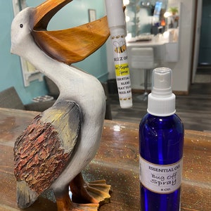 May include: A blue glass bottle with a white label that reads "Essential Oil Bug Off Spray 8 oz." and a white tube with a yellow label that reads "Buzz Off Bee Repellent Spray Essential Blend Spray to Keep Bees Away".