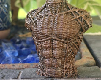 May include: A brown 3D printed sculpture of a human torso featuring a textured, woven filament pattern that mimics muscle definition. The figure is headless and armless, showcasing a detailed chest and abdominal structure with visible layers.