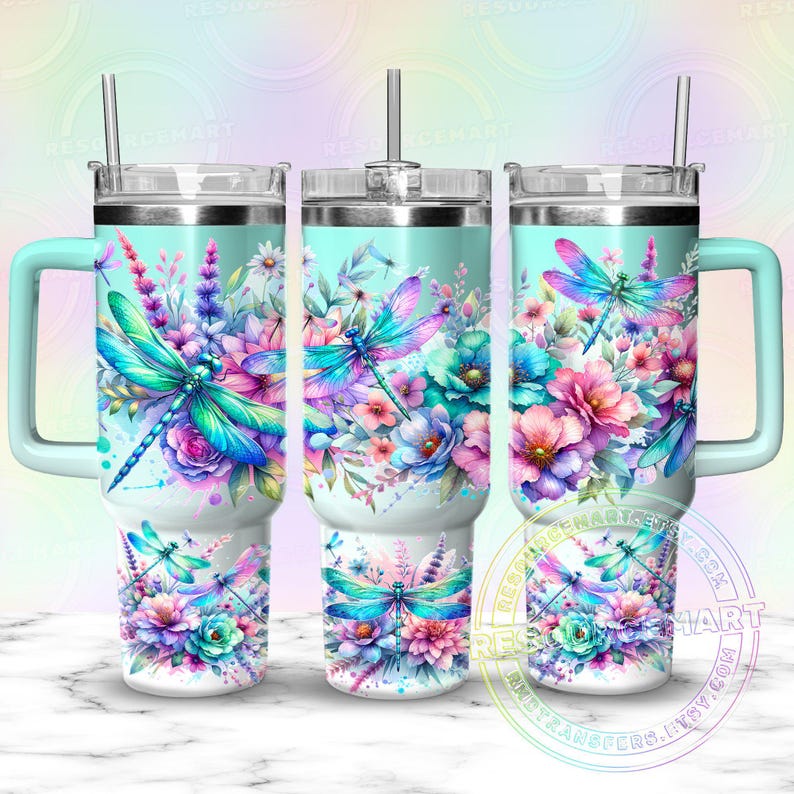 May include: Three insulated tumblers with teal handles and lids. Each tumbler features a watercolor design of dragonflies and flowers in shades of blue, pink, and purple. The design wraps around the tumblers.