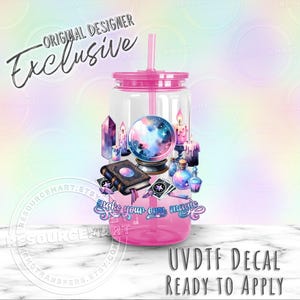 May include: A pink tumbler with a straw, featuring a colorful design of a crystal ball, candles, books, and the text "Make your own magic." The words "Original Designer Exclusive" and "UVDTF DECAL READY TO APPLY" are also visible.