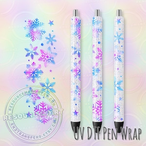 May include: Three pens with a white background and a snowflake design in shades of blue and purple. The pens have black tips and silver accents. The text "UV DTF PEN WRAP" is at the bottom.
