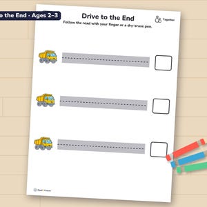 Drive to the End page with straight roads to trace, printed and lying on a wooden table with three crayons.