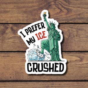 May include: A sticker featuring the Statue of Liberty in green, holding a torch and tablet, standing on a block of ice. Text reads "I PREFER MY ICE CRUSHED" in black and red.