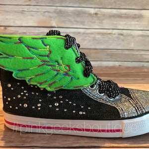 May include: Black high-top sneakers with a green felt wing attached to the side. The sneakers have silver glitter accents and rhinestones on the black canvas. The sneakers have a pink stripe on the white sole. #pinkgeeksboutique