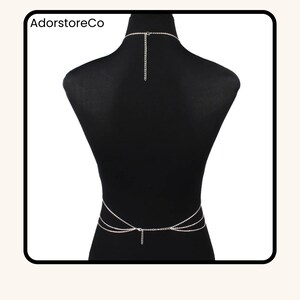 May include: A silver body chain with a necklace and waist chain design. The body jewelry is displayed on a black mannequin. The text "AdorstoreCo" is visible in the upper left corner.