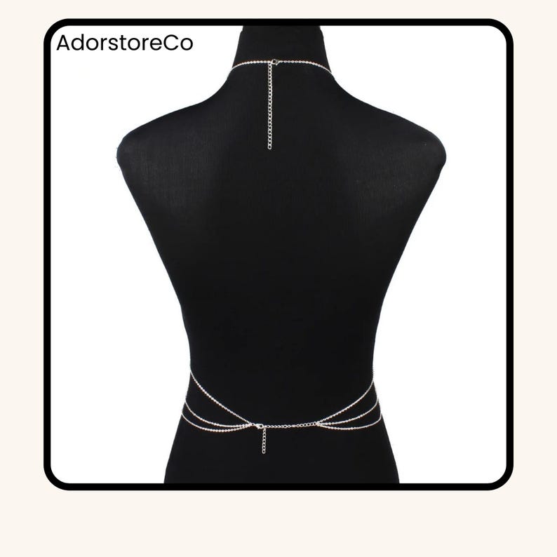 May include: A silver body chain with a necklace and waist chain design. The body jewelry is displayed on a black mannequin. The text "AdorstoreCo" is visible in the upper left corner.