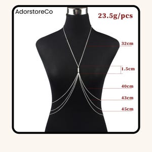 May include: Silver body chain necklace displayed on a mannequin. The necklace features multiple strands and a central design with small beads. Measurements are provided: 32cm, 1.5cm, 40cm, 43cm, and 45cm. The text "AdorstoreCo" and "23.5g/pcs" are visible.