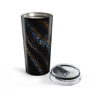 May include: A cylindrical stainless steel tumbler featuring a dark, iridescent snake scale pattern in shades of black, deep blue, and metallic bronze. The tumbler has a smooth, tapered body and comes with a clear, removable plastic lid with a sliding closure.