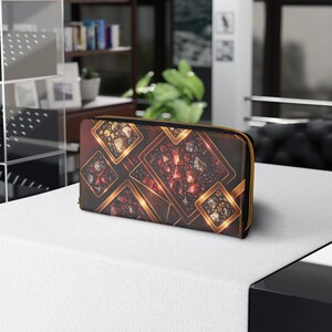 May include: A rectangular zip-around wallet featuring a dark background with a repeating pattern of gold-bordered squares containing clusters of red, orange, and brown gemstones. The wallet has a gold-toned zipper along the top and side edges.