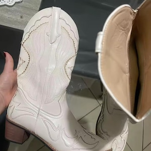 Step into the season with the ultimate statement piece. Our White Vintage Western Boots blend the rugged spirit of the frontier with high-fashion elegance. Featuring intricate tonal embroidery and a sophisticated pointed toe, these knee-high boots are designed to turn heads at weddings, festivals, or on a casual autumn stroll.