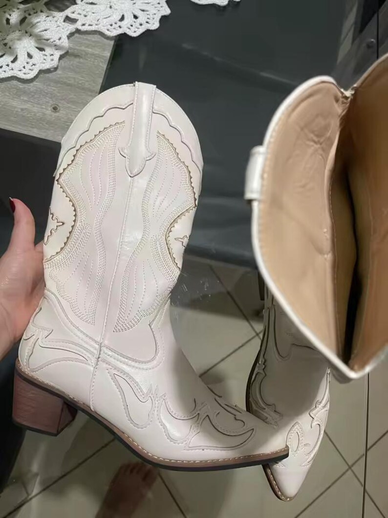 Step into the season with the ultimate statement piece. Our White Vintage Western Boots blend the rugged spirit of the frontier with high-fashion elegance. Featuring intricate tonal embroidery and a sophisticated pointed toe, these knee-high boots are designed to turn heads at weddings, festivals, or on a casual autumn stroll.