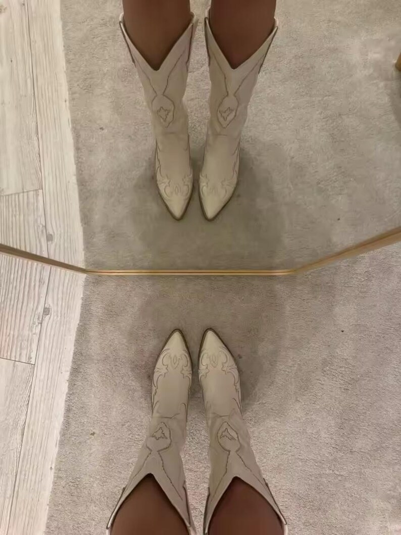 Step into the season with the ultimate statement piece. Our White Vintage Western Boots blend the rugged spirit of the frontier with high-fashion elegance. Featuring intricate tonal embroidery and a sophisticated pointed toe, these knee-high boots are designed to turn heads at weddings, festivals, or on a casual autumn stroll.
