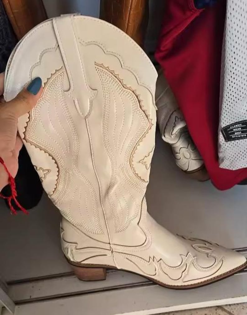 Step into the season with the ultimate statement piece. Our White Vintage Western Boots blend the rugged spirit of the frontier with high-fashion elegance. Featuring intricate tonal embroidery and a sophisticated pointed toe, these knee-high boots are designed to turn heads at weddings, festivals, or on a casual autumn stroll.