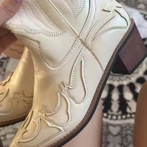 Step into the season with the ultimate statement piece. Our White Vintage Western Boots blend the rugged spirit of the frontier with high-fashion elegance. Featuring intricate tonal embroidery and a sophisticated pointed toe, these knee-high boots are designed to turn heads at weddings, festivals, or on a casual autumn stroll.